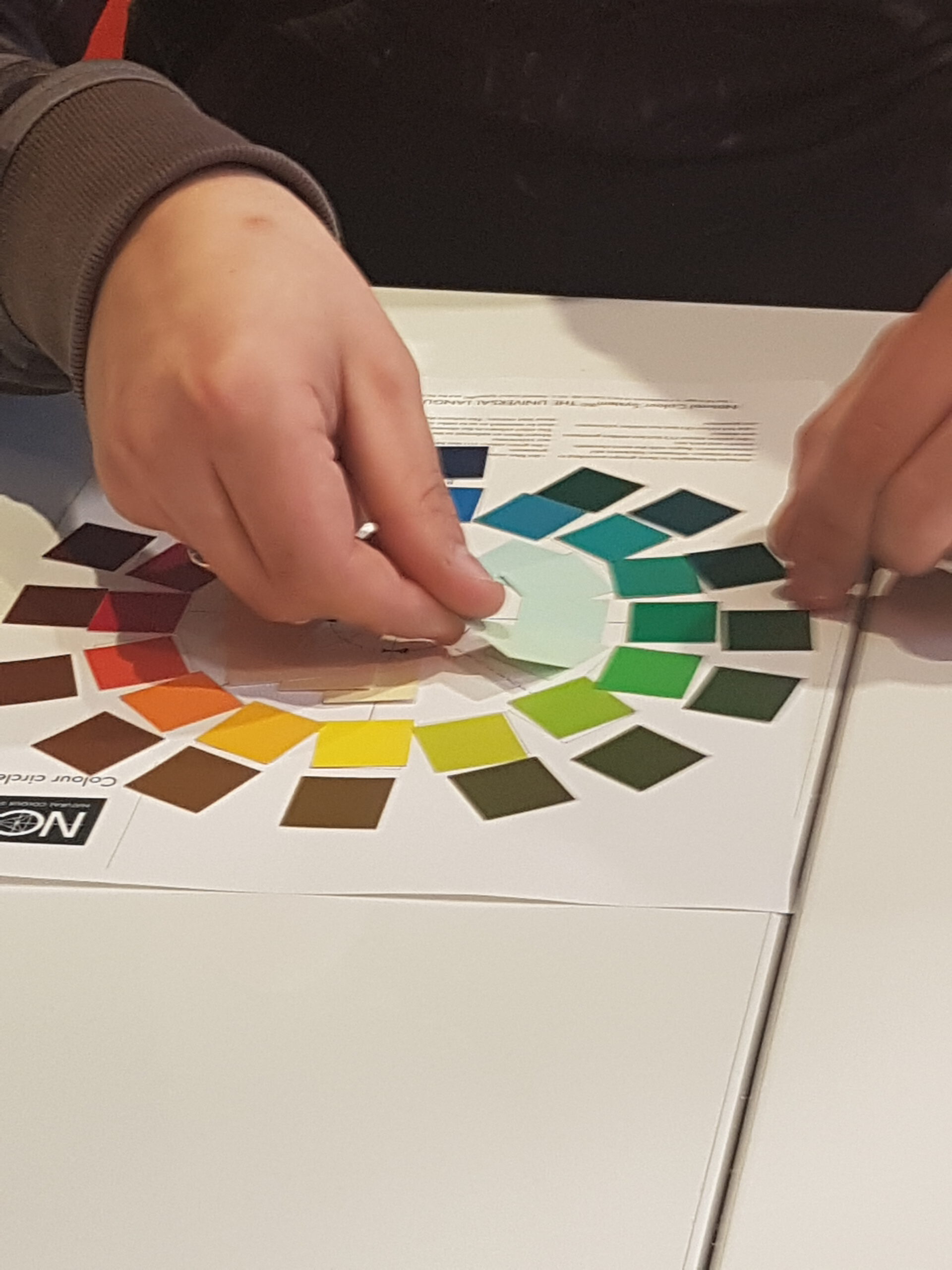 Docent legt kleurleer uit aan studenten met kleurwaaiers en spectrofotometer